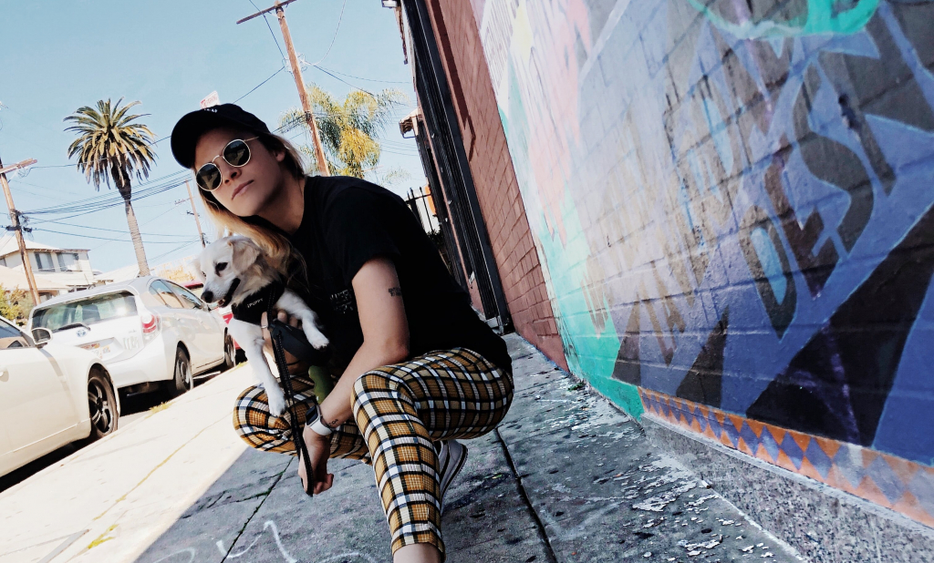 woman with dog sitting by wall with grafitti