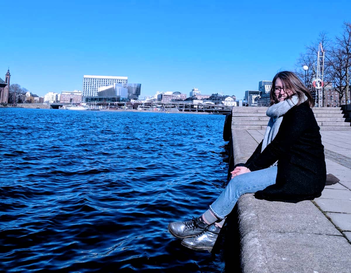 woman sitting by the edge of water in a city