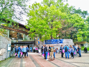 Groups of young people standing outside building and green trees