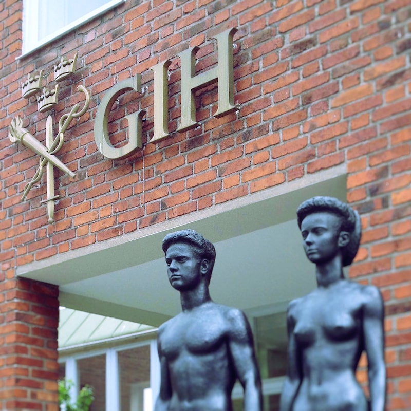 Two athletic statues standing in front of a brick building