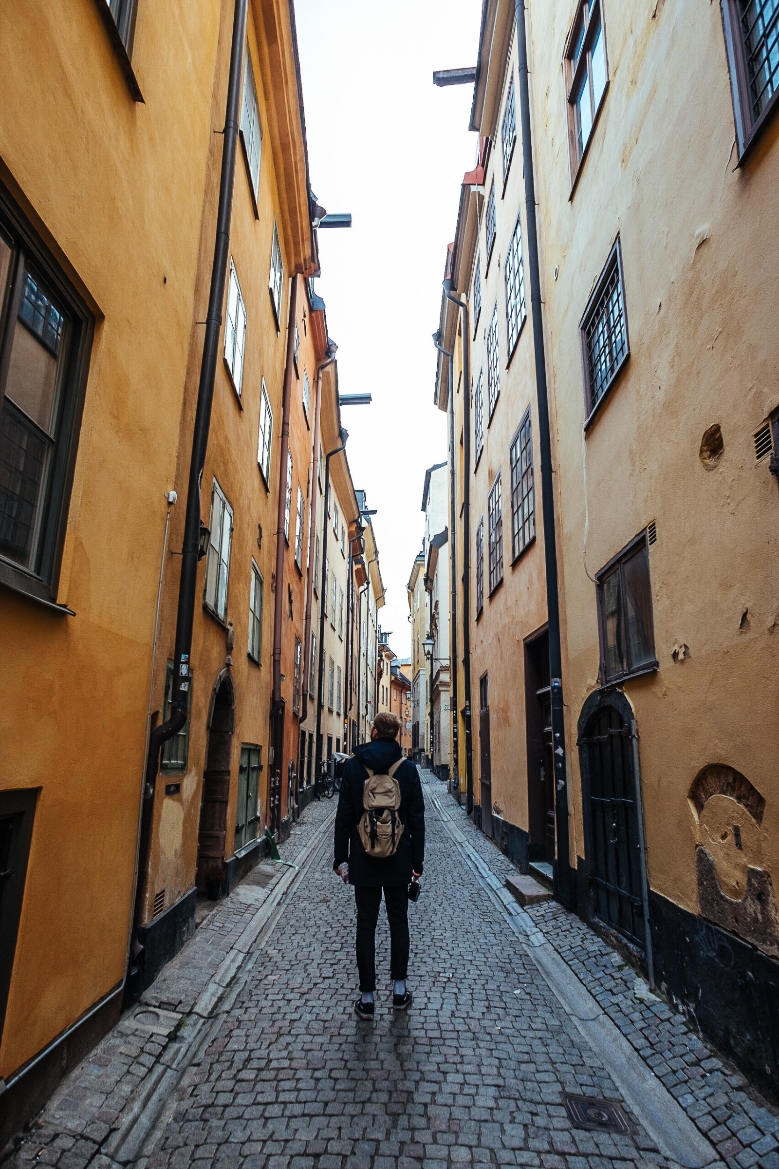 Man with backpack standing in narrow alley street in Old Town Stockholm